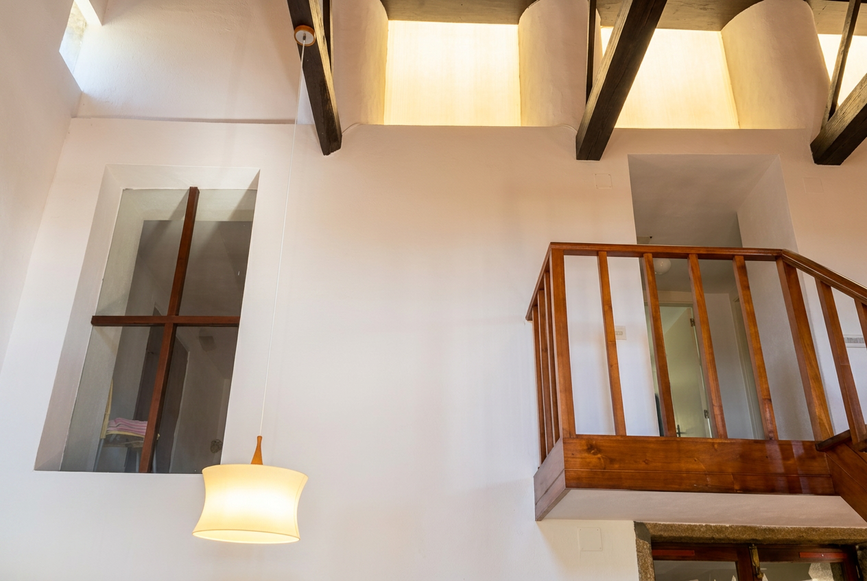 Doble altura con vigas de madera oscura en casa rural gallega